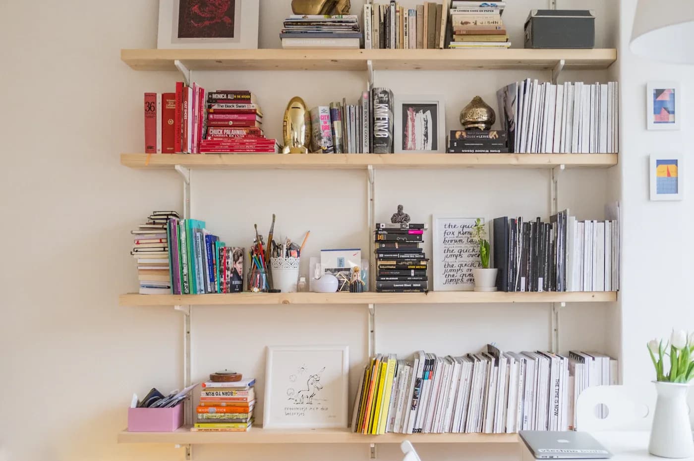 چیدمان قفسه کتاب با کتابهای رنگی روی طبقههای چوبی روشن